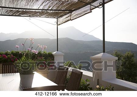 Table and chairs on balcony overlooking mountains View Large Photo Image Stock Photograph - Table and chairs on balcony overlooking mountains. Fotosearch