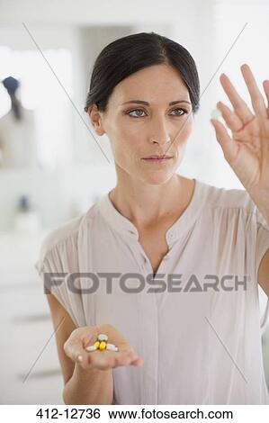 Stock Photograph - Woman examining pills in bathroom. Fotosearch