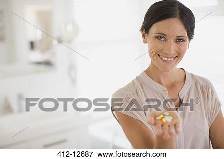 Stock Photo - Woman holding handful of pills. Fotosearch