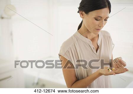 Woman looking at pills in hand View Large Photo Image Picture - Woman looking at pills in hand. Fotosearch