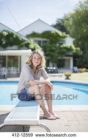 Woman sitting on diving board at poolside View Large Photo Image Stock Photo - Woman sitting on diving board at poolside. Fotosearch