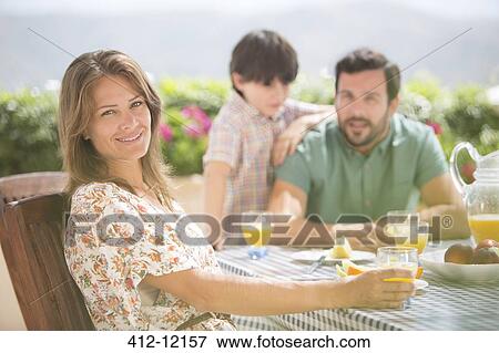 Stock Photo - Woman smiling at patio table. Fotosearch