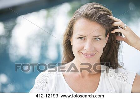 Woman smiling with hand in hair at poolside View Large Photo Image Stock Image - Woman smiling with hand in hair at poolside. Fotosearch