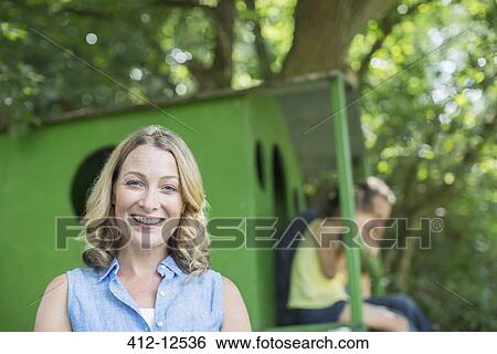 Stock Photograph - Woman smiling with treehouse in background. Fotosearch