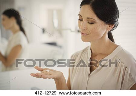 Woman taking pill in bathroom View Large Photo Image Stock Photo - Woman taking pill in bathroom. Fotosearch