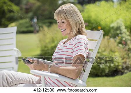 Woman using cell phone in garden View Large Photo Image Stock Image - Woman using cell phone in garden. Fotosearch