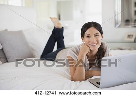 Woman using laptop on bed View Large Photo Image Stock Image - Woman using laptop on bed. Fotosearch