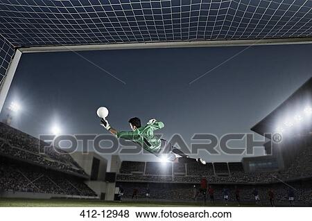Goalie jumping for ball in soccer net View Large Photo Image Stock Photo - Goalie jumping for ball in soccer net. Fotosearch