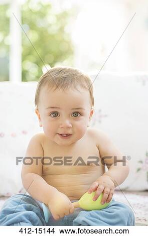 Picture - Baby boy sitting on sofa. Fotosearch