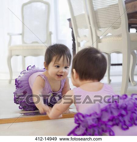 Stock Photo - Baby girl admiring herself in mirror. Fotosearch
