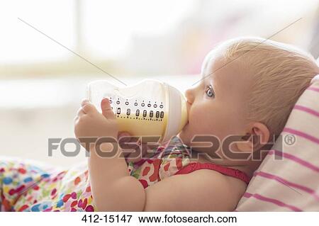 Baby girl drinking from bottle on sofa View Large Photo Image Stock Photo - Baby girl drinking from bottle on sofa. Fotosearch
