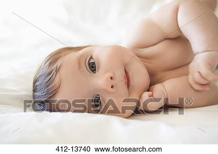 Stock Image - Baby girl laying on bed. Fotosearch