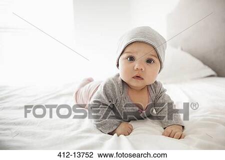 Baby girl laying on bed View Large Photo Image Stock Image - Baby girl laying on bed. Fotosearch