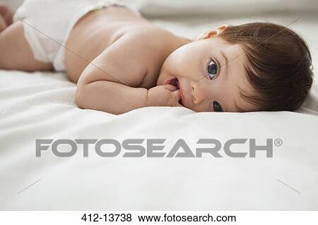 Baby girl laying on bed View Large Photo Image Stock Photo - Baby girl laying on bed. Fotosearch