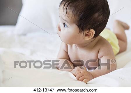Baby girl laying on bed View Large Photo Image Stock Photo - Baby girl laying on bed. Fotosearch
