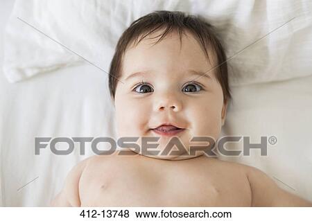 Stock Photo - Baby girl laying on bed. Fotosearch