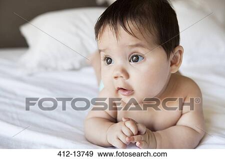 Stock Photo - Baby girl laying on bed. Fotosearch