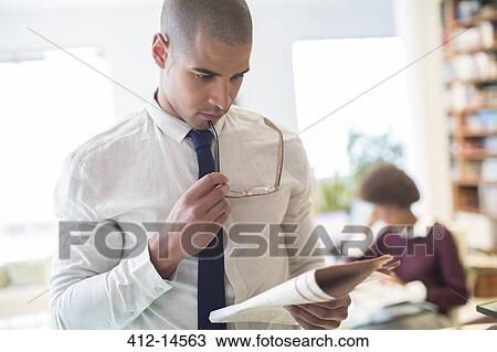 Stock Image - Businessman reading newspaper in living room. Fotosearch