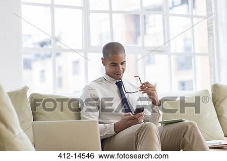Businessman using cell phone on sofa View Large Photo Image Stock Photograph - Businessman using cell phone on sofa. Fotosearch