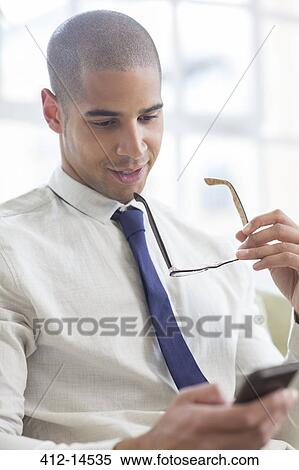 Businessman using cell phone on sofa View Large Photo Image Stock Photography - Businessman using cell phone on sofa. Fotosearch