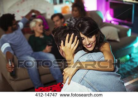 Couple hugging in living room at party View Large Photo Image Stock Photo - Couple hugging in living room at party. Fotosearch