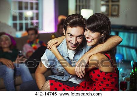 Stock Photography - Couple hugging in living room at party. Fotosearch