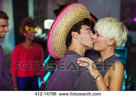 Stock Photograph - Couple kissing at party. Fotosearch