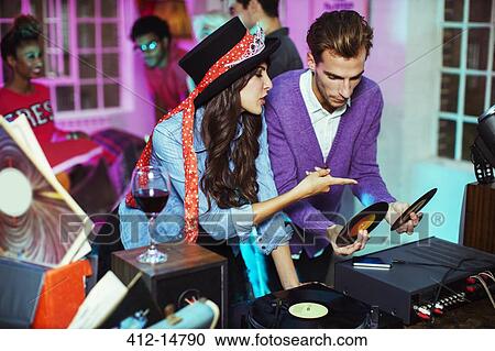 Stock Image - Couple playing records at party. Fotosearch