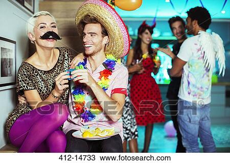 Stock Image - Couple wearing costumes at party. Fotosearch