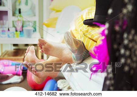 Stock Image - Couple's feet sticking out from bed covers. Fotosearch