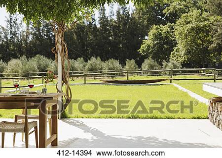 Dining table and chairs on patio overlooking backyard View Large Photo Image Picture - Dining table and chairs on patio overlooking backyard. Fotosearch