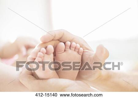 Stock Image - Father cradling baby boy's feet. Fotosearch