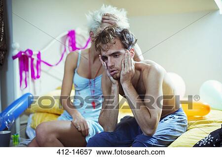 Hungover couple sitting on bed the morning after a party View Large Photo Image Stock Photo - Hungover couple sitting on bed the morning after a party. Fotosearch