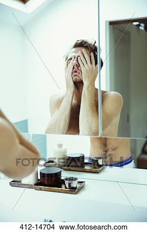 Hungover man covering face at mirror View Large Photo Image Picture - Hungover man covering face at mirror. Fotosearch
