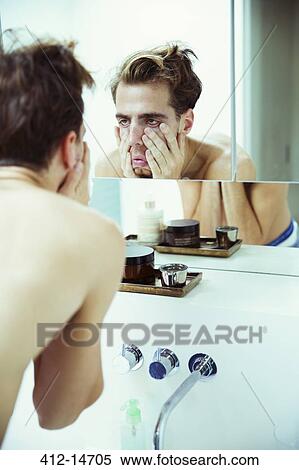 Stock Photography - Hungover man examining himself in mirror. Fotosearch