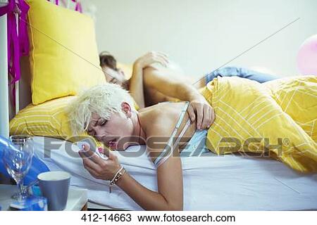Hungover woman checking cell phone in bed the morning after a party View Large Photo Image Stock Image - Hungover woman checking cell phone in bed the morning after a party. Fotosearch