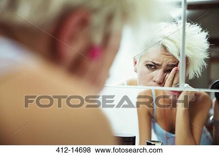 Hungover woman examining herself in mirror View Large Photo Image Stock Photo - Hungover woman examining herself in mirror. Fotosearch