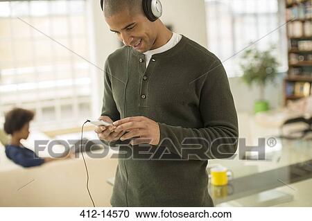 Man listening to headphones in living room View Large Photo Image Stock Image - Man listening to headphones in living room. Fotosearch