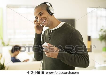 Man listening to headphones in living room View Large Photo Image Stock Photography - Man listening to headphones in living room. Fotosearch