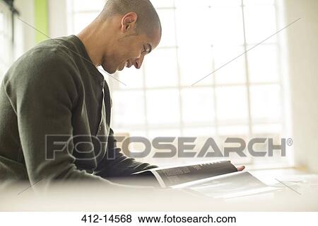 Man reading magazine on sofa View Large Photo Image Stock Photo - Man reading magazine on sofa. Fotosearch