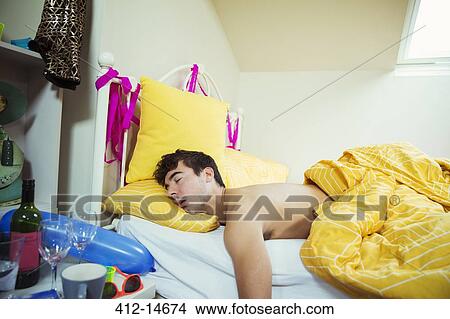 Picture - Man sleeping in bed after party. Fotosearch