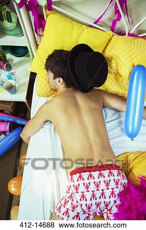 Stock Photo - Man sleeping on bed after party. Fotosearch