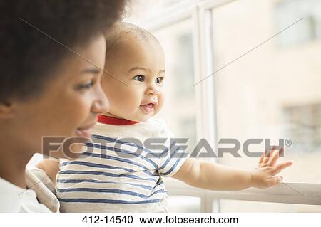 Stock Image - Mother and baby boy looking out window. Fotosearch