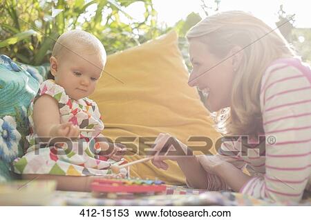 Stock Image - Mother and baby girl playing with xylophone outdoors. Fotosearch