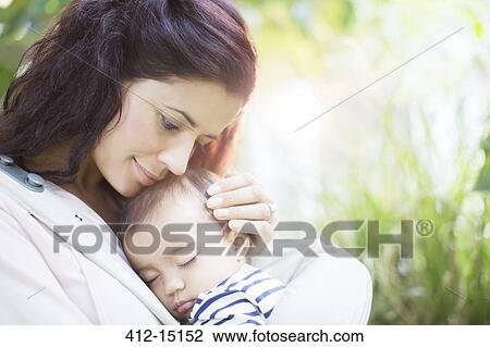 Mother holding sleeping baby girl View Large Photo Image Stock Image - Mother holding sleeping baby girl. Fotosearch