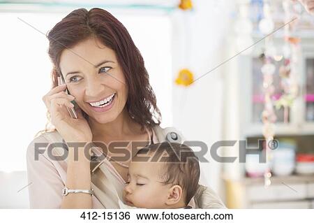 Mother with sleeping baby girl talking on cell phone View Large Photo Image Stock Photograph - Mother with sleeping baby girl talking on cell phone. Fotosearch