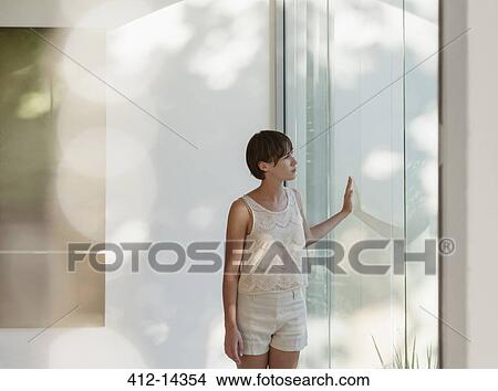 Pensive woman standing at sunny window View Large Photo Image Picture - Pensive woman standing at sunny window. Fotosearch