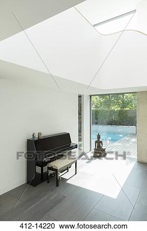 Stock Image - Piano and Buddha statue in modern house. Fotosearch