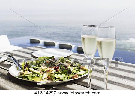 Plate of salad and glasses of champagne on table outdoors View Large Photo Image Stock Photo - Plate of salad and glasses of champagne on table outdoors. Fotosearch