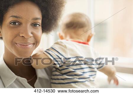 Smiling mother holding baby boy View Large Photo Image Stock Image - Smiling mother holding baby boy. Fotosearch